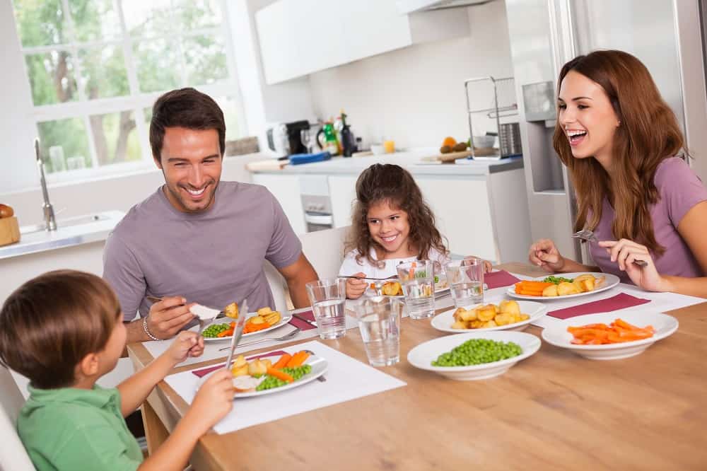 A family laughing together over dinner at their kitchen table